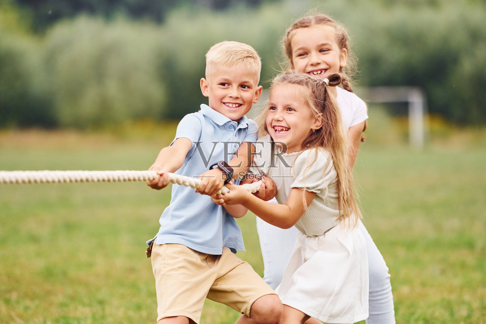 微笑着，玩拔河游戏。孩子们白天一起在操场上玩得很开心照片摄影图片