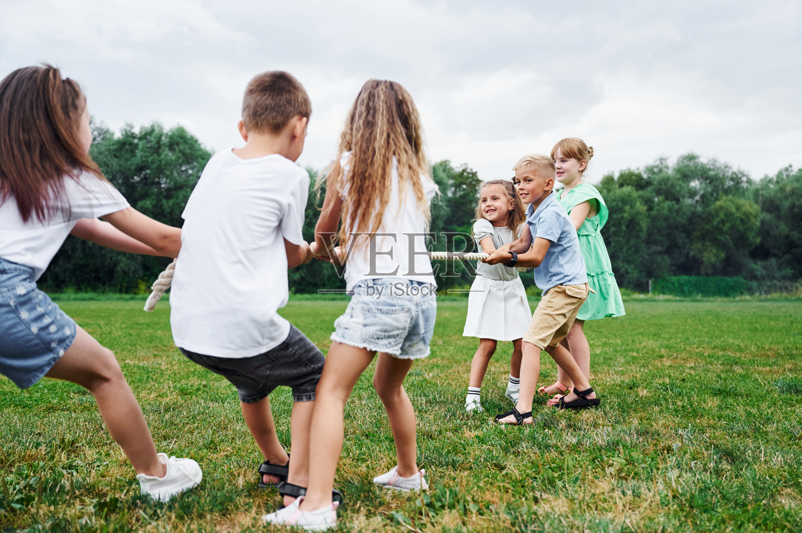 抓着绳子，做着游戏。孩子们白天一起在操场上玩得很开心照片摄影图片