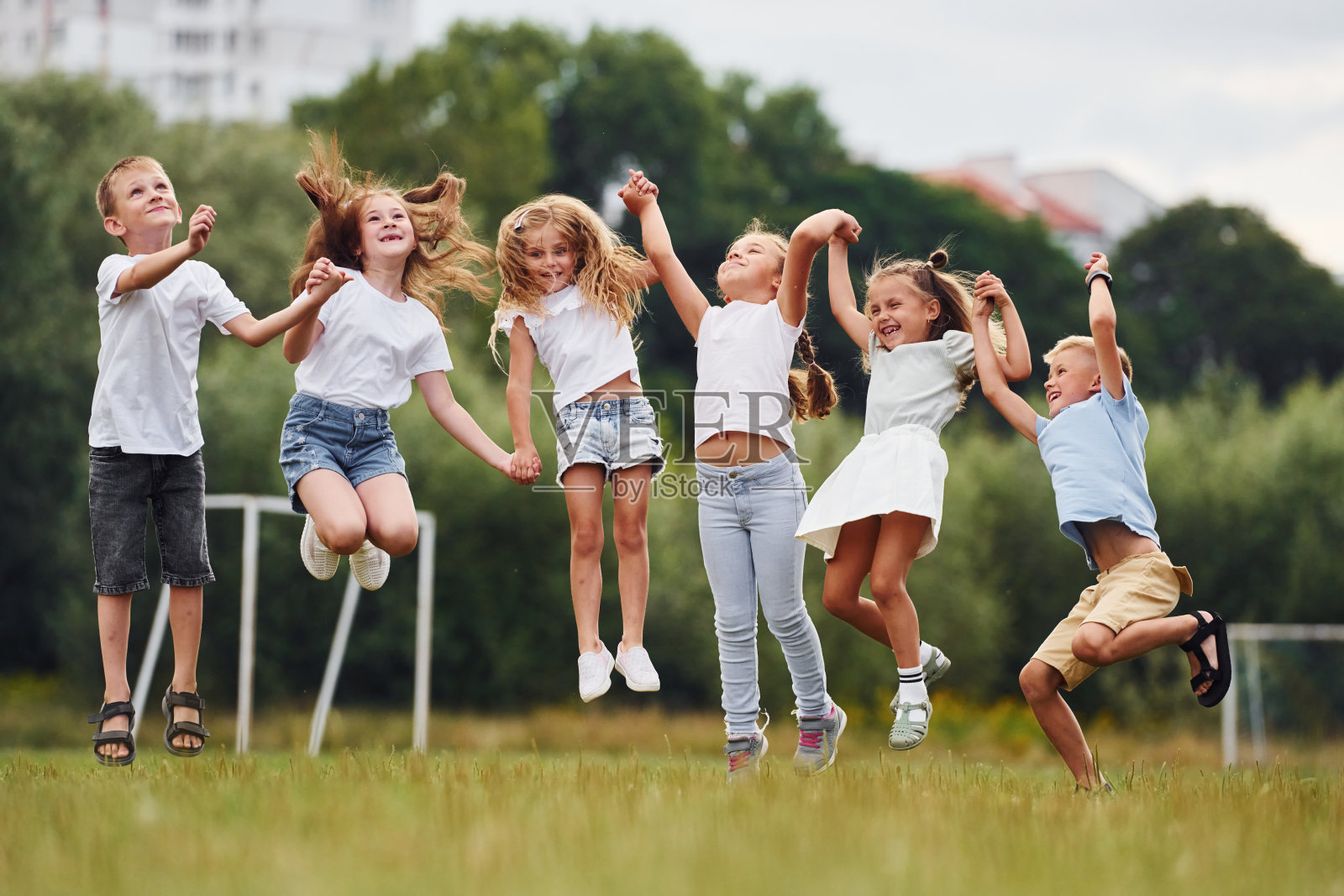 手牵着手一起跳。孩子们白天一起在操场上玩得很开心照片摄影图片