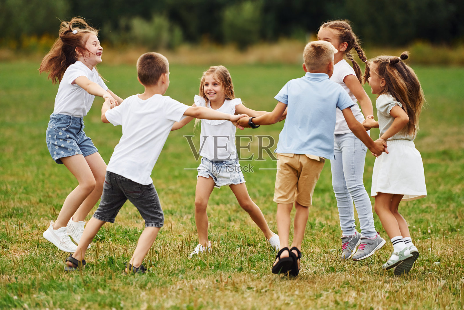 绕着圈子跑，手牵着手。孩子们白天一起在操场上玩得很开心照片摄影图片