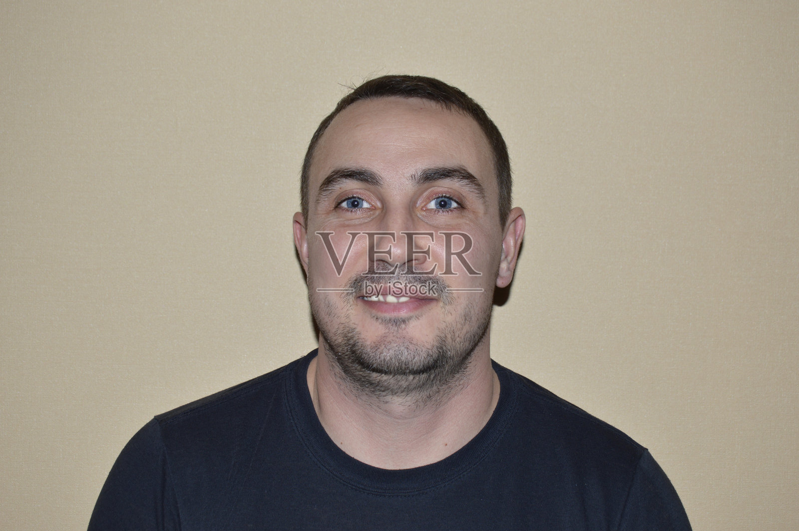 一个年轻英俊的男人的肖像，有轻微的胡茬，微笑和幸福的眼睛照片摄影图片