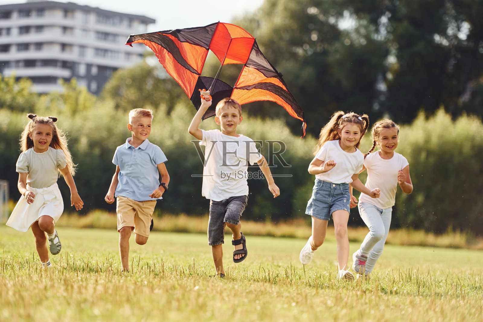 一起运行。一群孩子在绿地上奔跑和玩风筝照片摄影图片