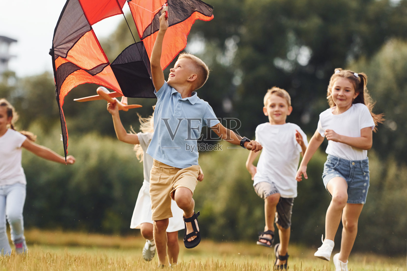 一群孩子在绿地上奔跑和玩风筝照片摄影图片