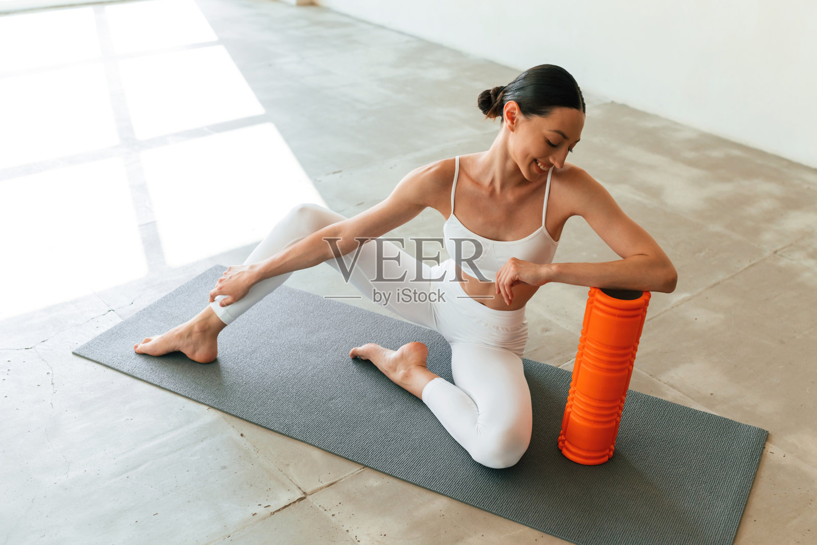 带有橙色泡沫滚轮。身材苗条的年轻女子在演播室里穿着健身服照片摄影图片