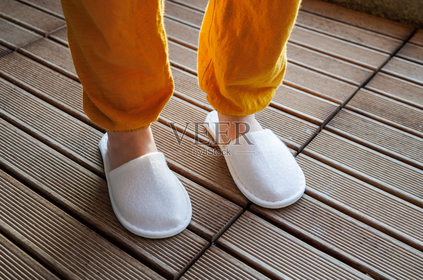 穿着拖鞋的孩子的脚站在地板上照片摄影图片