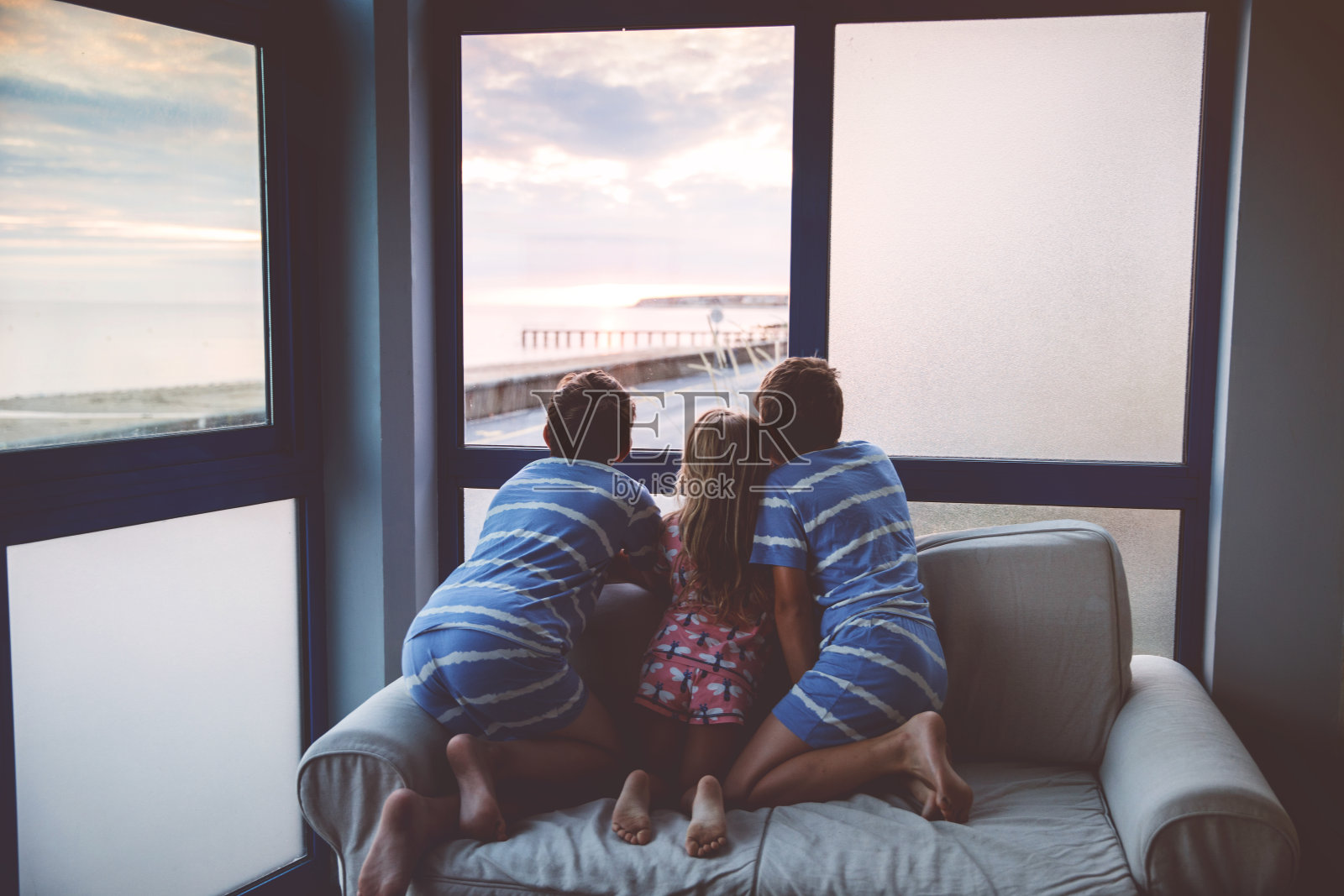 三个孩子在露台或阳台上看日出。两个孩子，男孩和幼儿园的女孩看着地平线上的太阳。快乐的孩子们在海滩边放松，家人欣赏美丽的景色。照片摄影图片