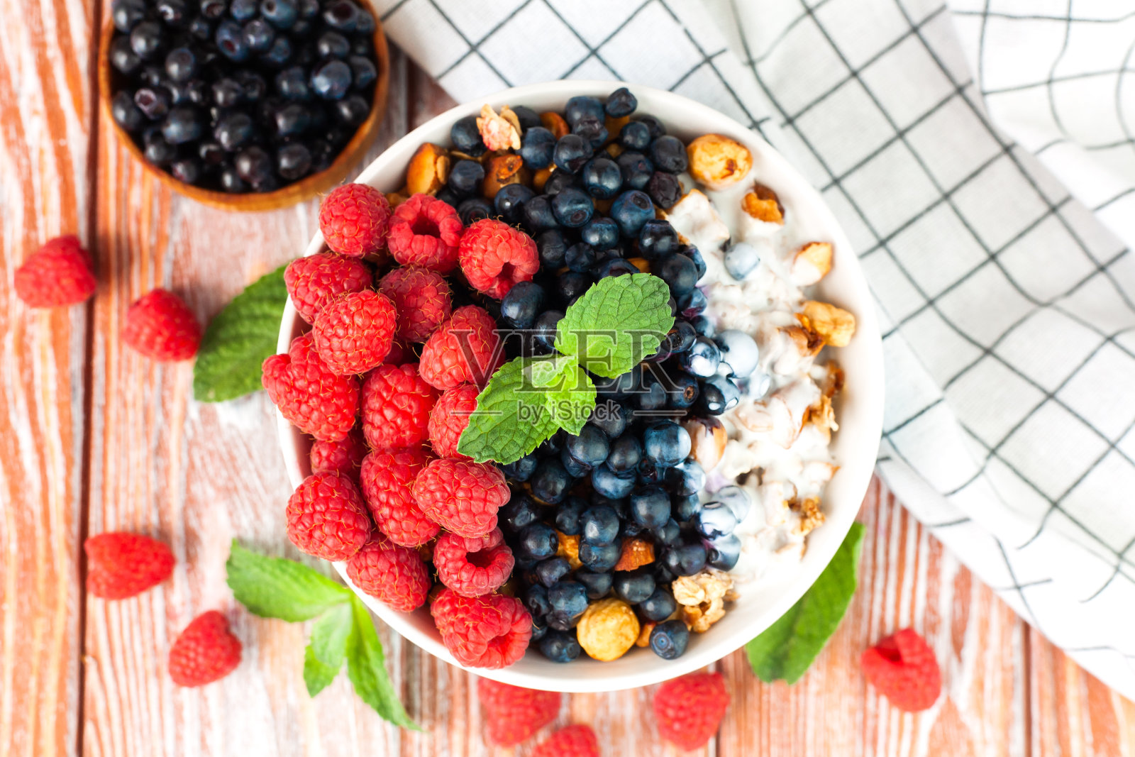 一碗格兰诺拉麦片，配上覆盆子、蓝莓和酸奶。健康美味的早餐。失去。前视图。照片摄影图片