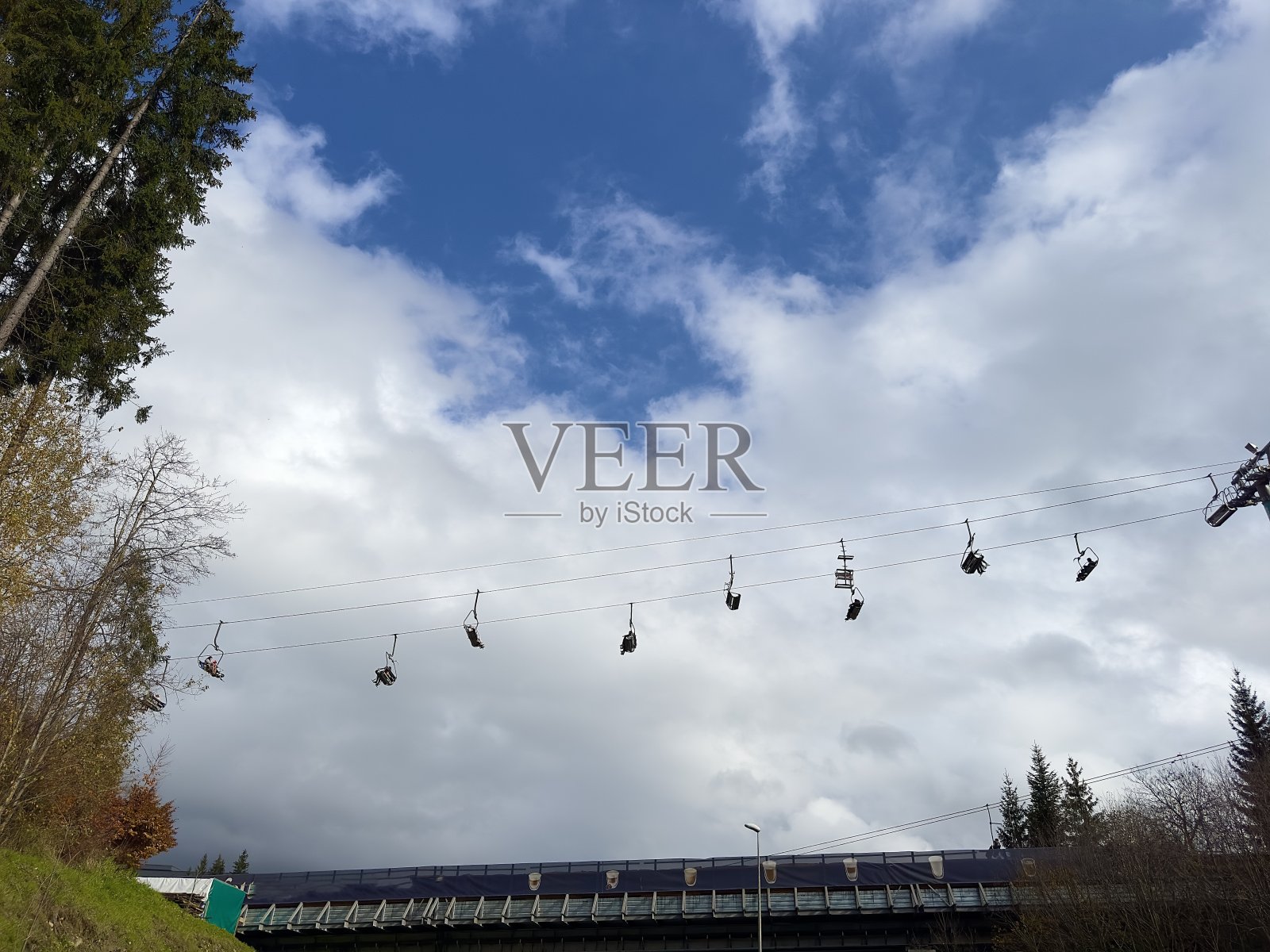 在云和阳光下的山上滑雪缆车照片摄影图片