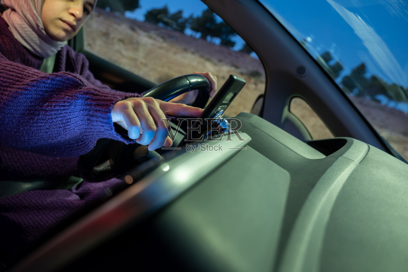 怀孕的阿拉伯穆斯林妇女晚上开车，穿着冬衣，戴着头巾，系着安全带，自信地开车，感觉很安全照片摄影图片