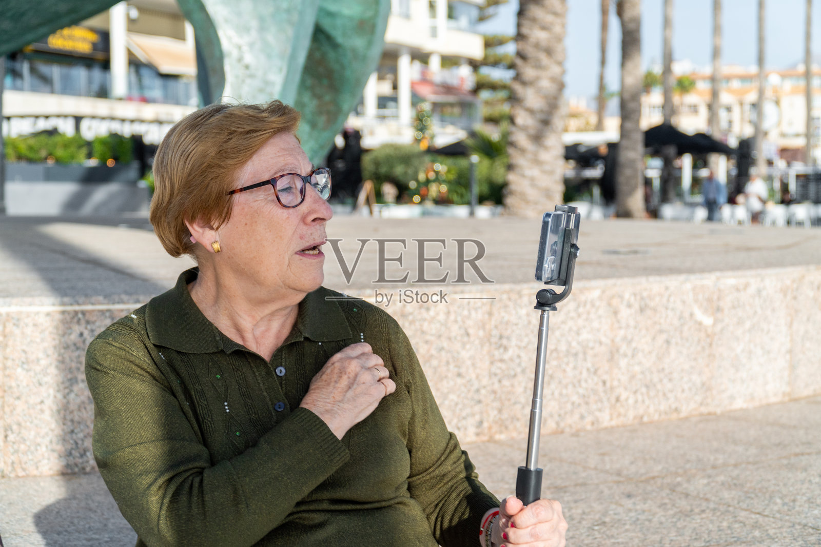 开朗的老妇人在户外用手机直播照片摄影图片