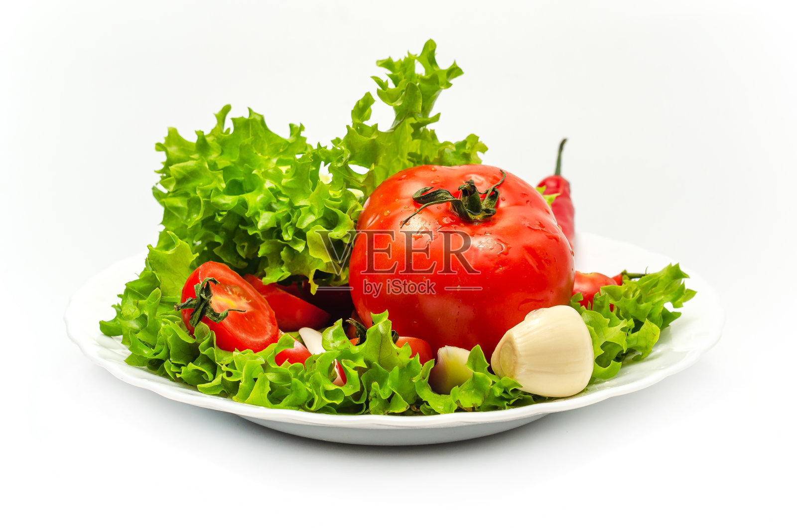 白色盘子里的蔬菜被隔离在白色的背景上。前视图。西红柿，胡椒，沙拉，大蒜。照片摄影图片