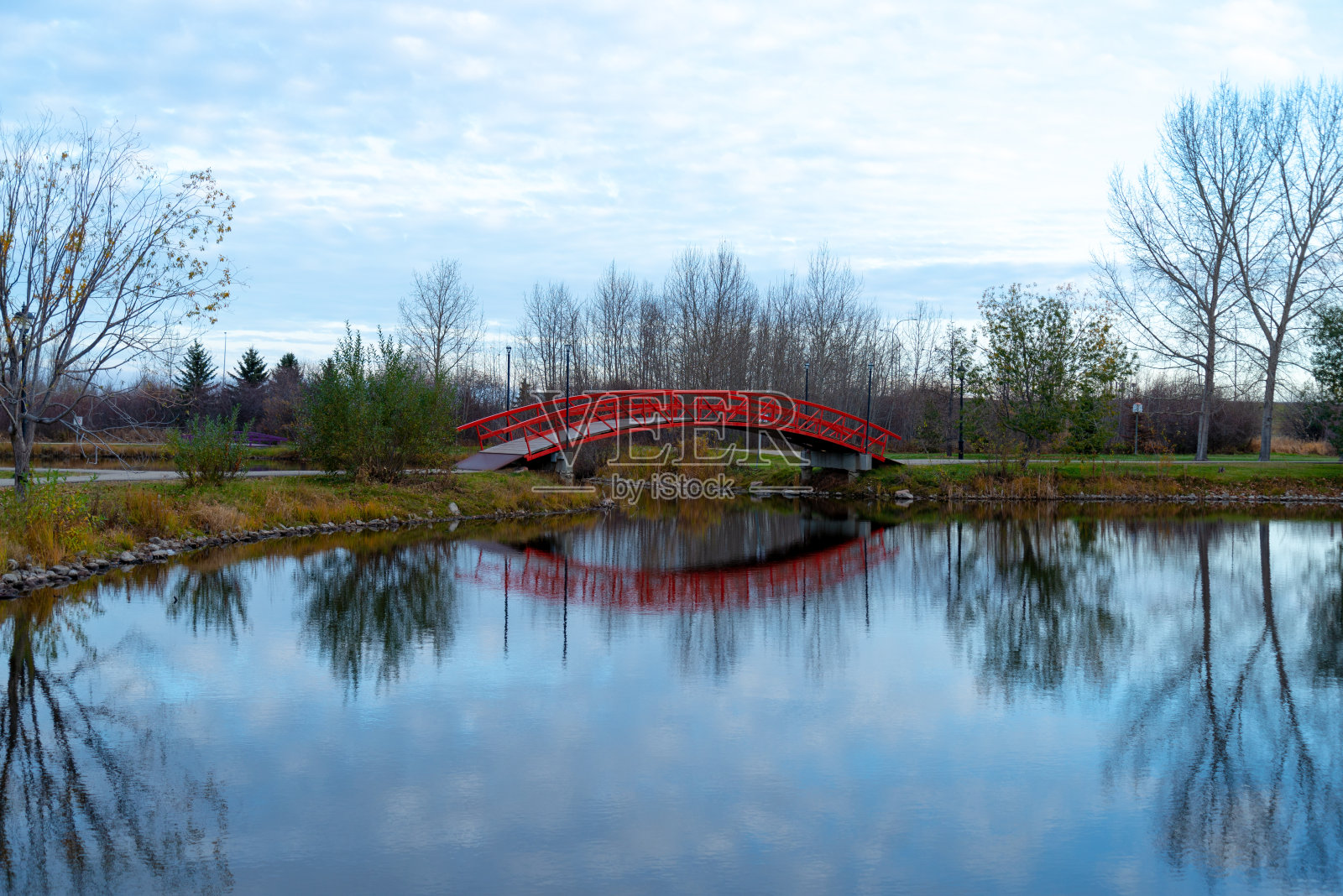 一座充满活力的红色桥梁横跨在宁静的湖面上照片摄影图片