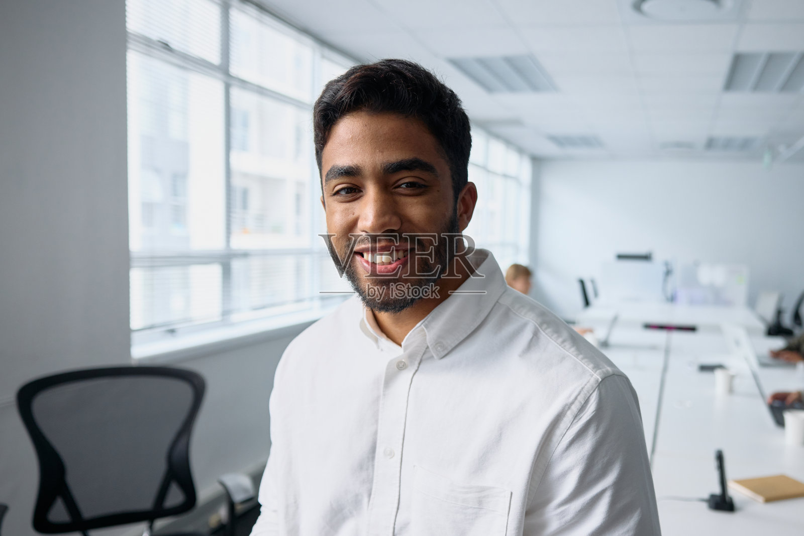 穿着职业装的快乐的年轻商人在办公室看着镜头的肖像照片摄影图片