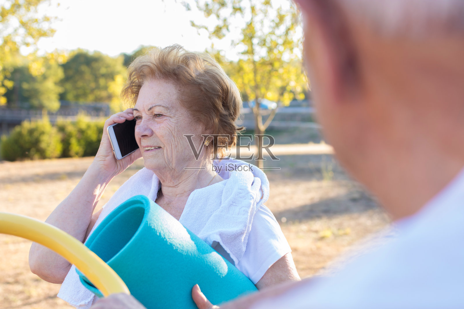 手持手机进行户外运动的老妇人照片摄影图片