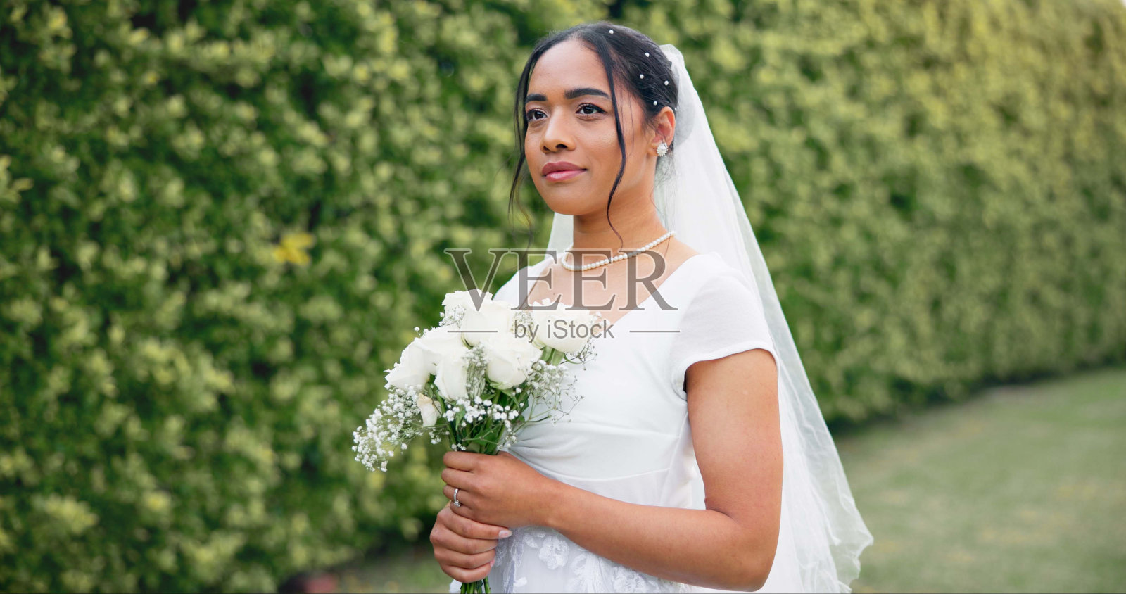 花园婚礼，新娘手持玫瑰花束，微笑着庆祝爱情、未来和承诺。户外婚礼，兴奋而快乐的女人带着鲜花，自然而美丽照片摄影图片