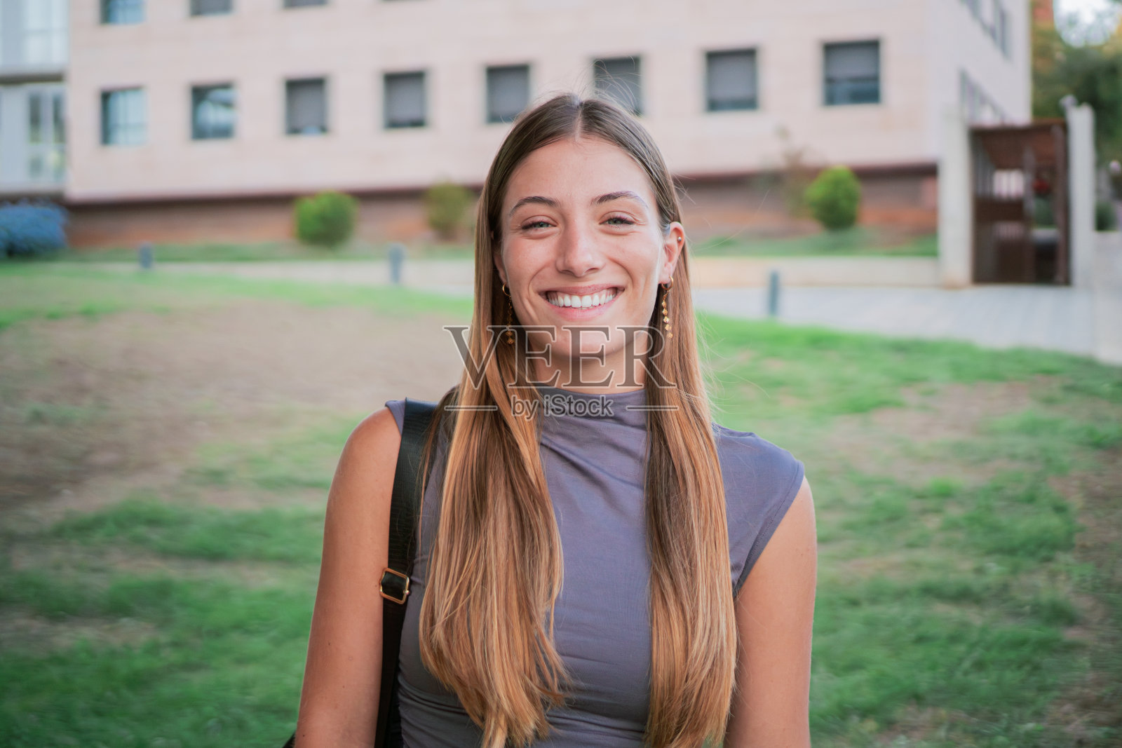 成功的年轻女学生肖像，积极自信的微笑在校园。年轻的白人女性看着镜头，表情愉快，为大学学习而兴奋照片摄影图片
