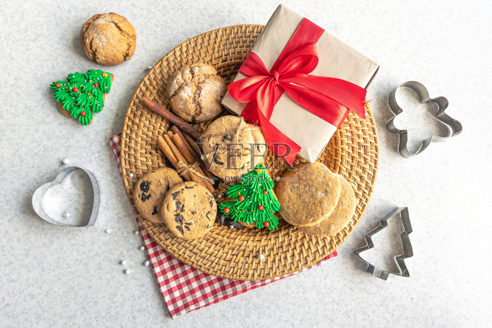 节日的圣诞饼干和礼盒放在厨房桌子上的柳条盘子里。照片摄影图片