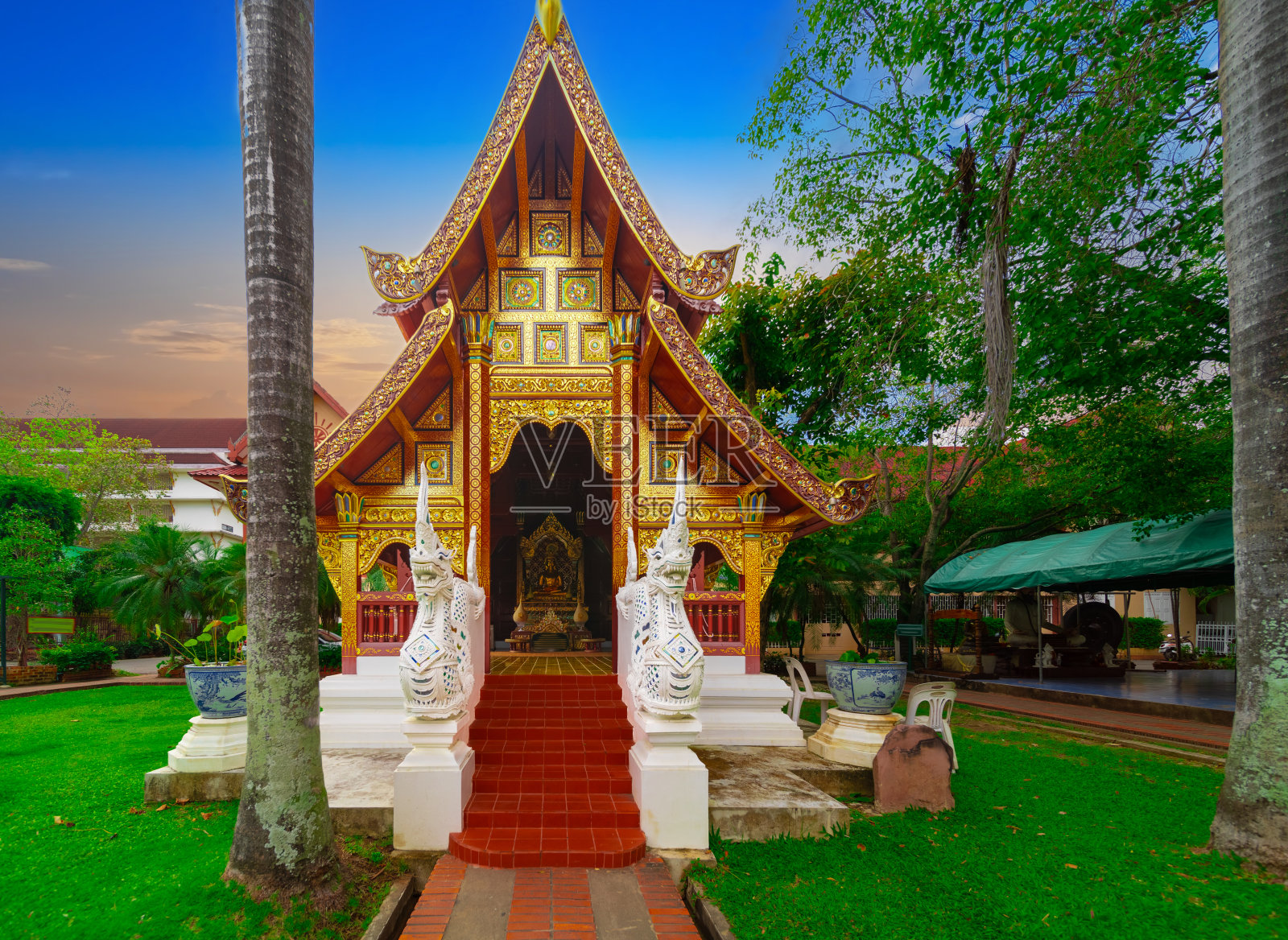 泰国清迈美丽的吴哥佛寺。装饰着美丽华丽的红色、金色和蓝色。美丽的日落照片摄影图片