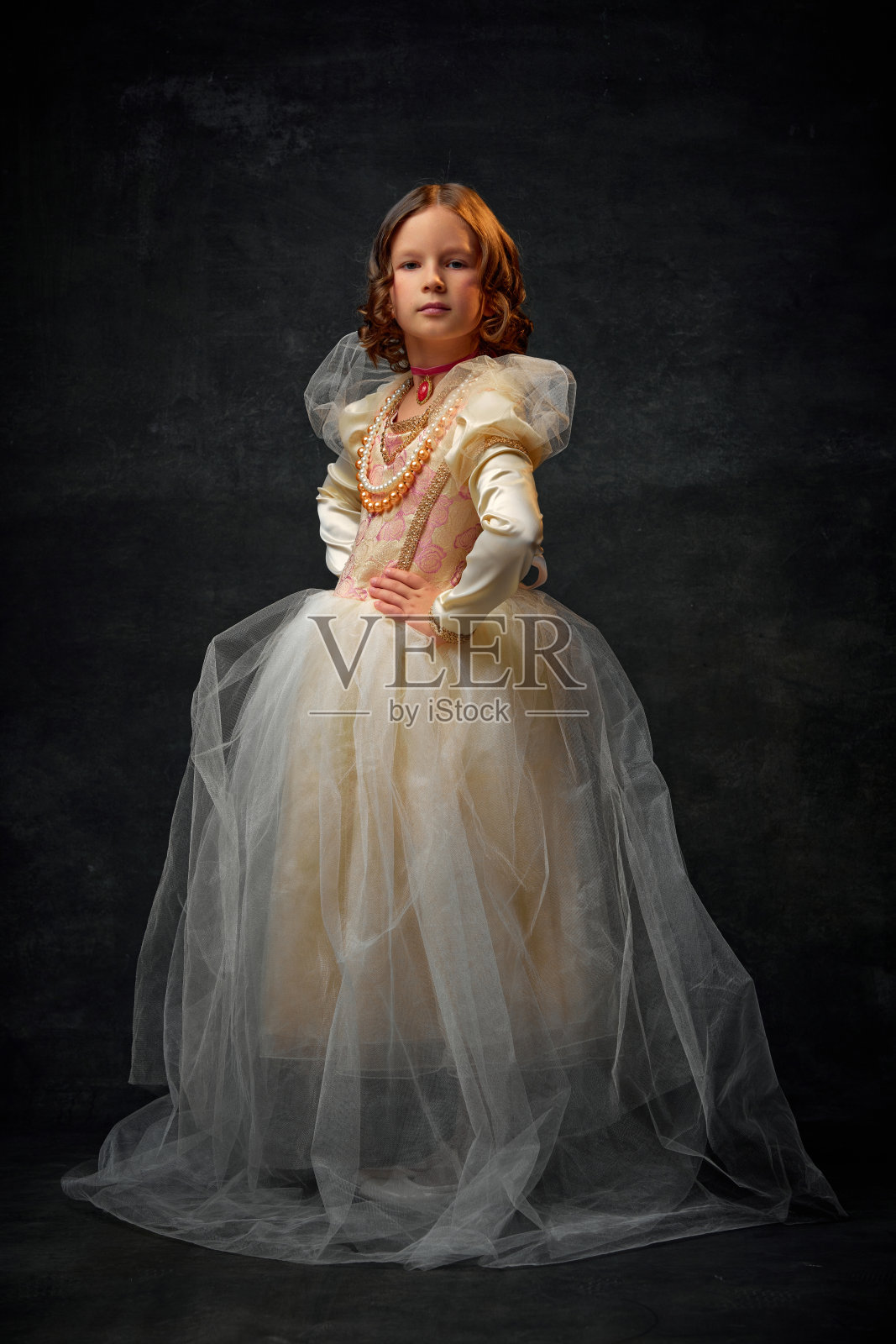 小女孩的全身画像，穿着老式的礼服，饰品在复古的背景下摆姿势，像皇室成员一样。照片摄影图片