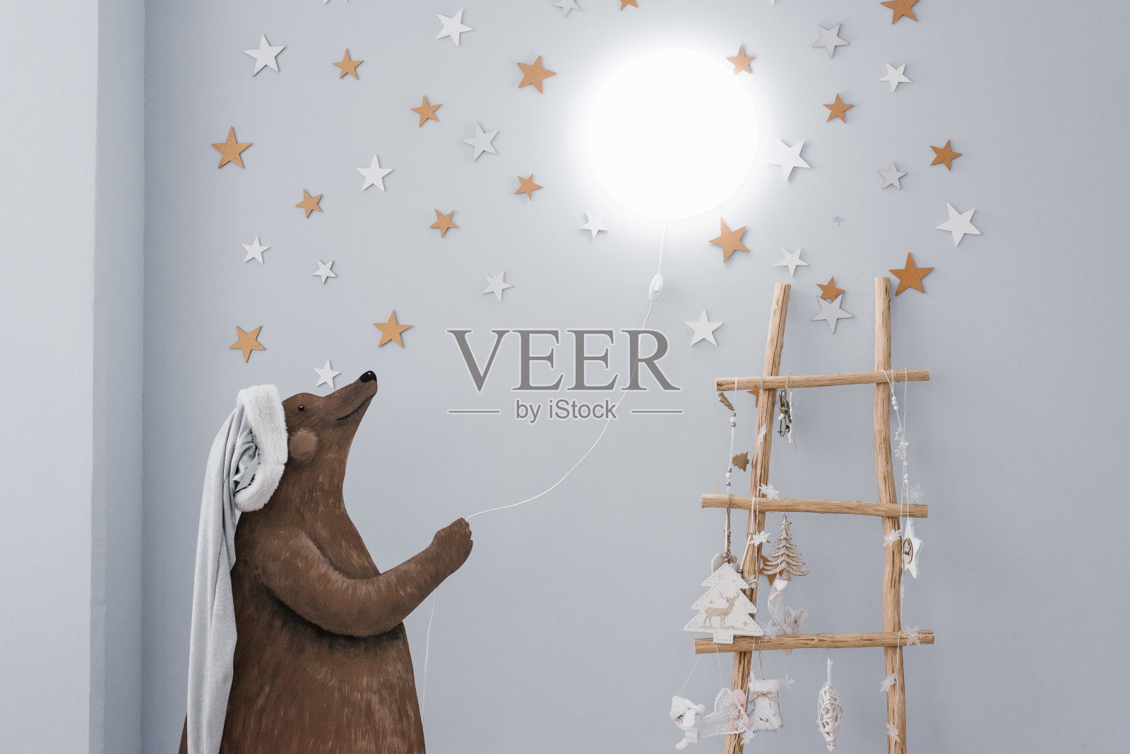 孩子们房间里的创意灯。画中的熊手里拿着一根绳子，墙上挂着一盏灯。圣诞装饰照片摄影图片