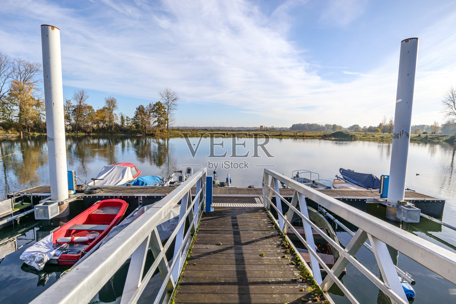 桥朝着码头在湖上停泊的船只，平坦的田野在蓝天的背景照片摄影图片