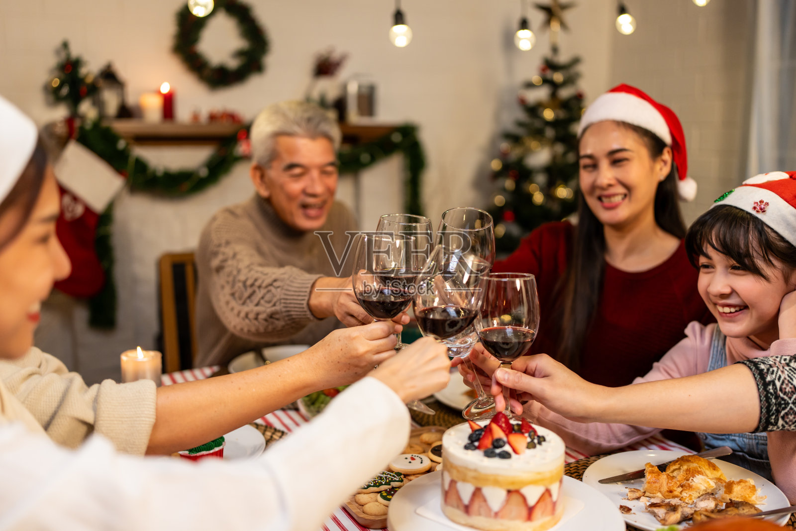亚洲家庭在圣诞晚会上给小女儿送礼盒。漂亮的小女孩在吃饭时收到亲戚的礼物，一起在餐桌上庆祝节日感恩节照片摄影图片