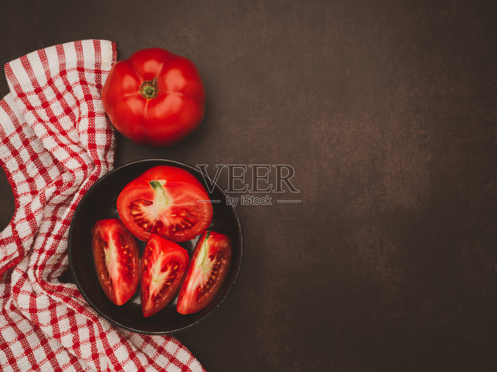 桌子上的黑碗里装着新鲜的西红柿照片摄影图片