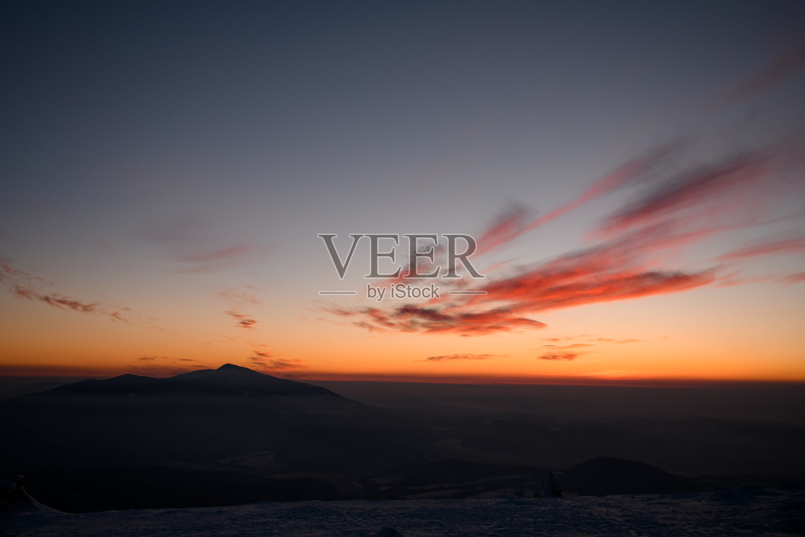 黄昏时分，雾气和明亮的云包围着冬季山脉的雄伟景象照片摄影图片