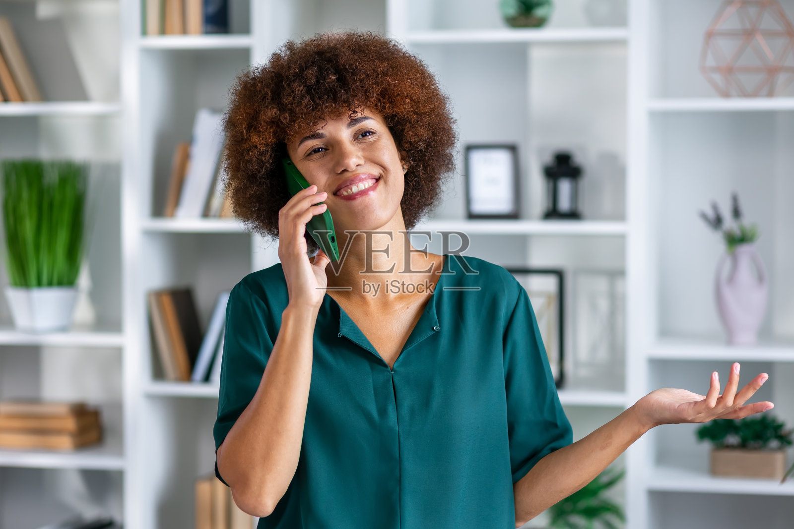 年轻的女商人在办公室打电话。微笑的非洲裔美国女商人在手机上愉快地交谈。照片摄影图片