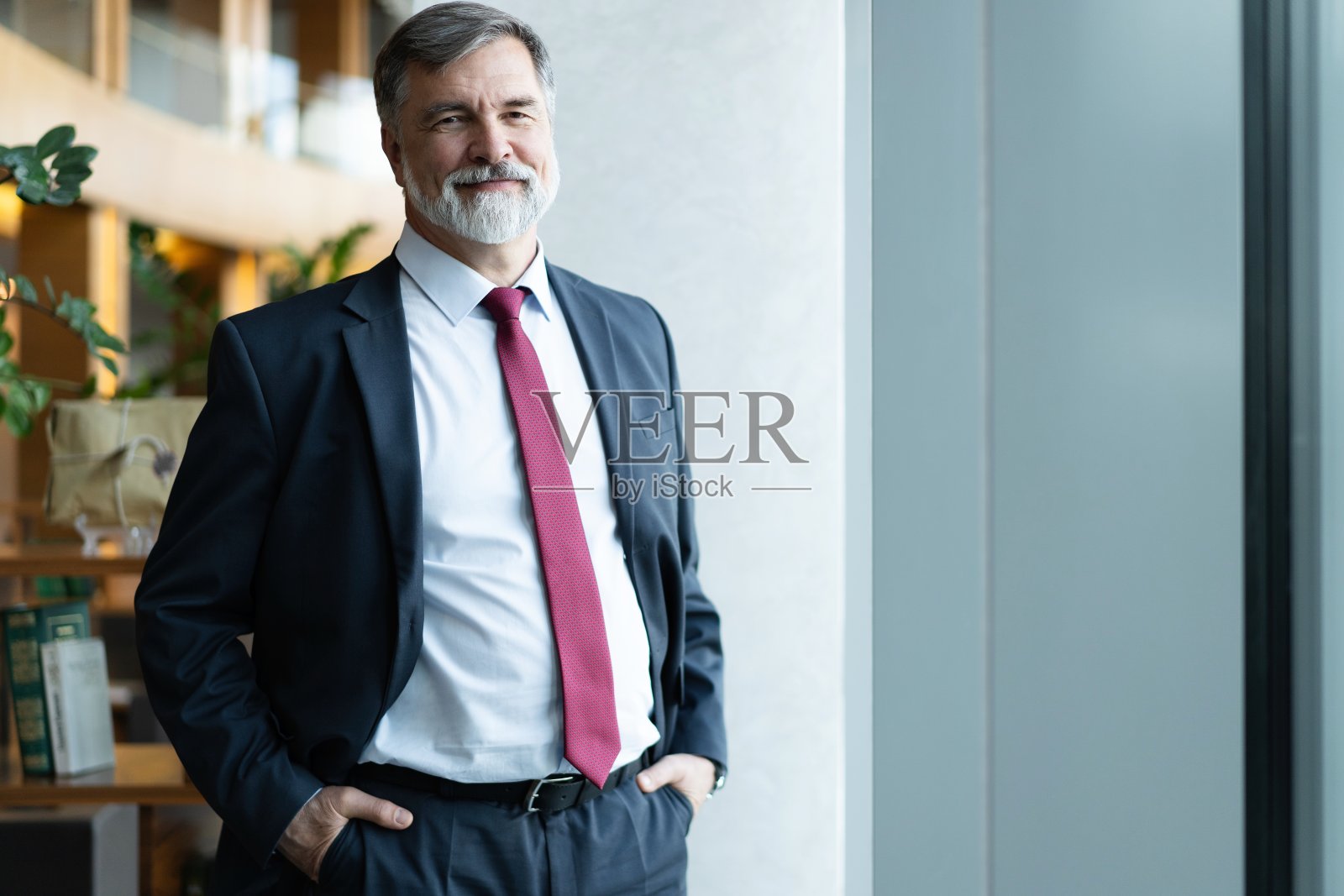 一个自信成熟的商人站在现代化的办公室里照片摄影图片
