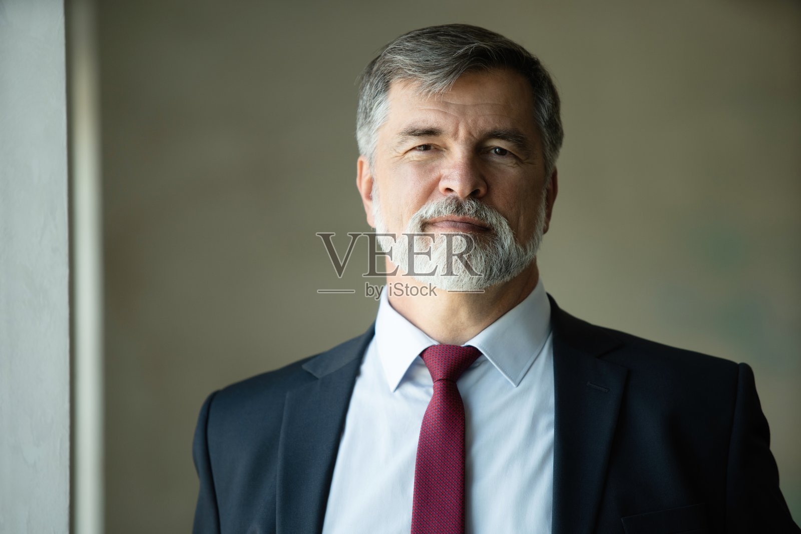 一个自信成熟的商人站在现代化的办公室里照片摄影图片