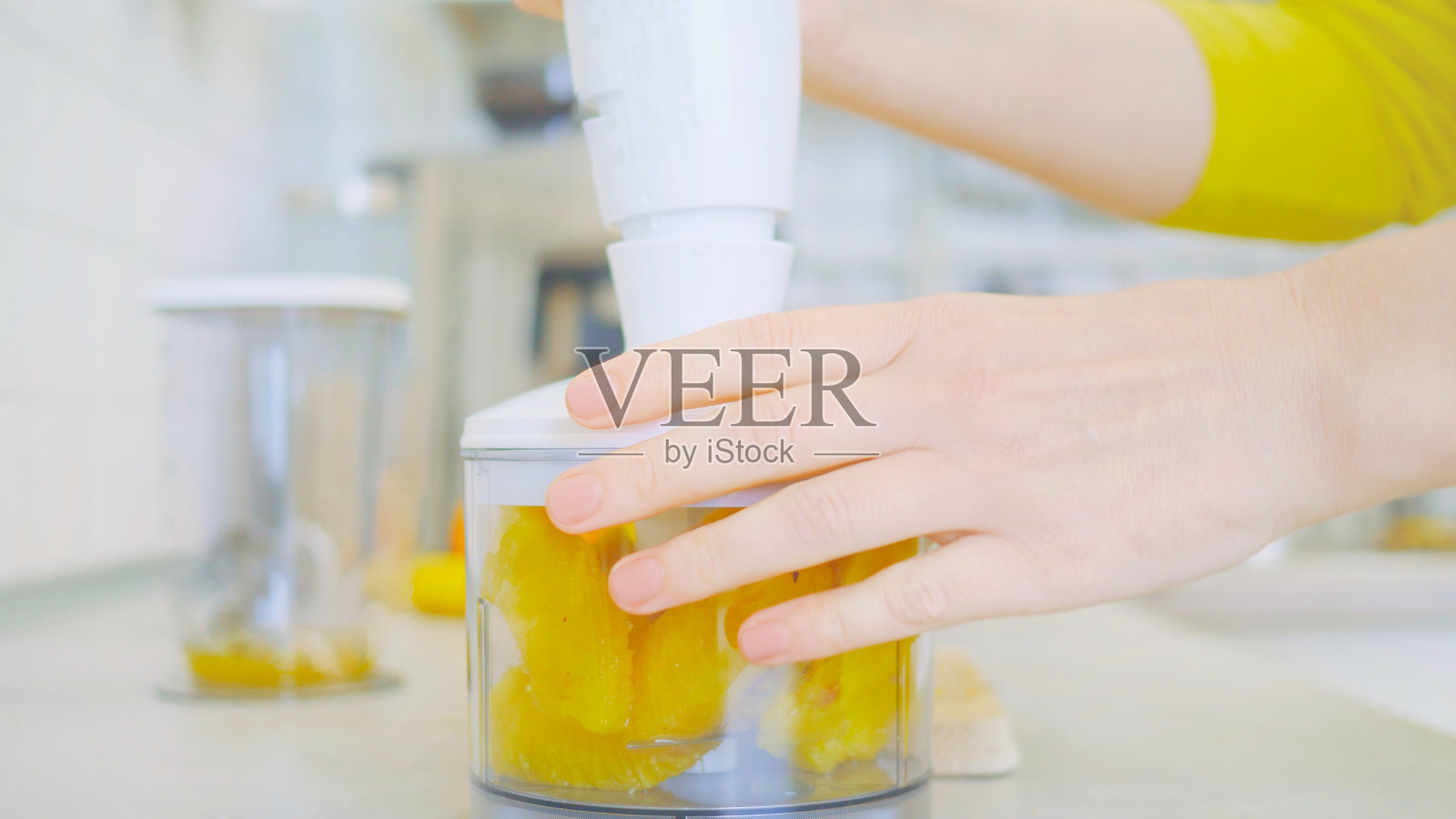 厨房里，一名妇女在木制砧板上切菠萝，周围是其他水果和搅拌机。她准备了健康、富含维生素、清爽的冰沙。宣传营养和健康饮食照片摄影图片