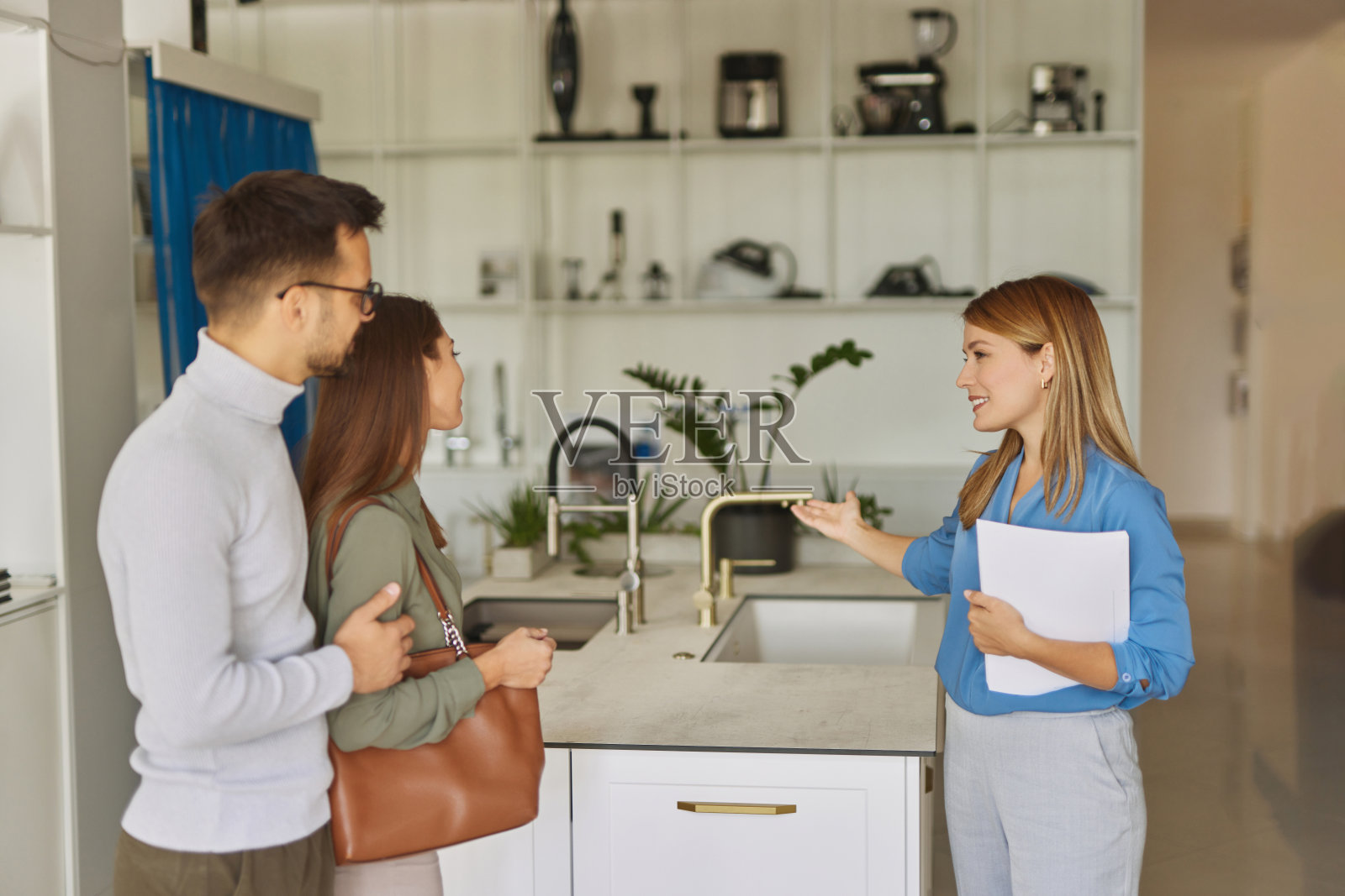 女店员帮助年轻夫妇选择新的厨房水龙头照片摄影图片
