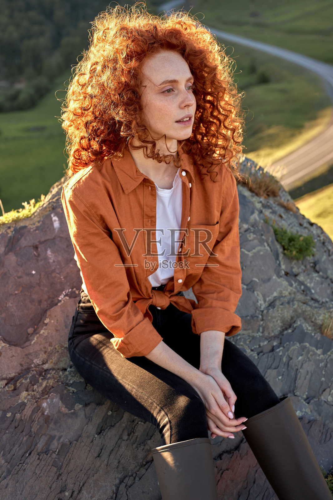 女徒步者坐在山上欣赏山顶的景色，坐得很放松照片摄影图片