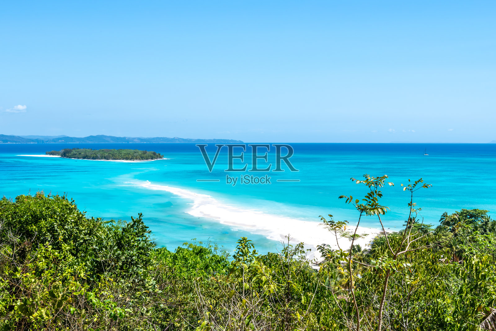 原始的，天堂般的白色沙滩，被绿松石蓝色，清澈的大海包围，从一个绿色岛屿的小山上拍摄。Nosy Be, Nosy Iranja，马达加斯加，非洲。照片摄影图片