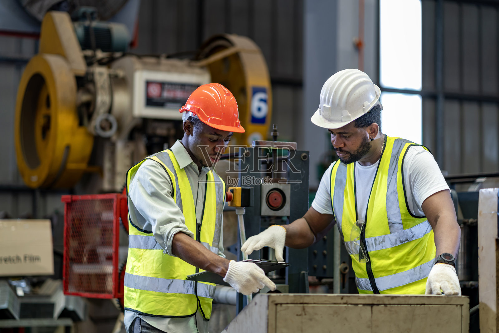 在安全工业屋顶工厂内工作的非裔美国工业工人正在用自动监视器检查金属板卷成型机的设置值照片摄影图片