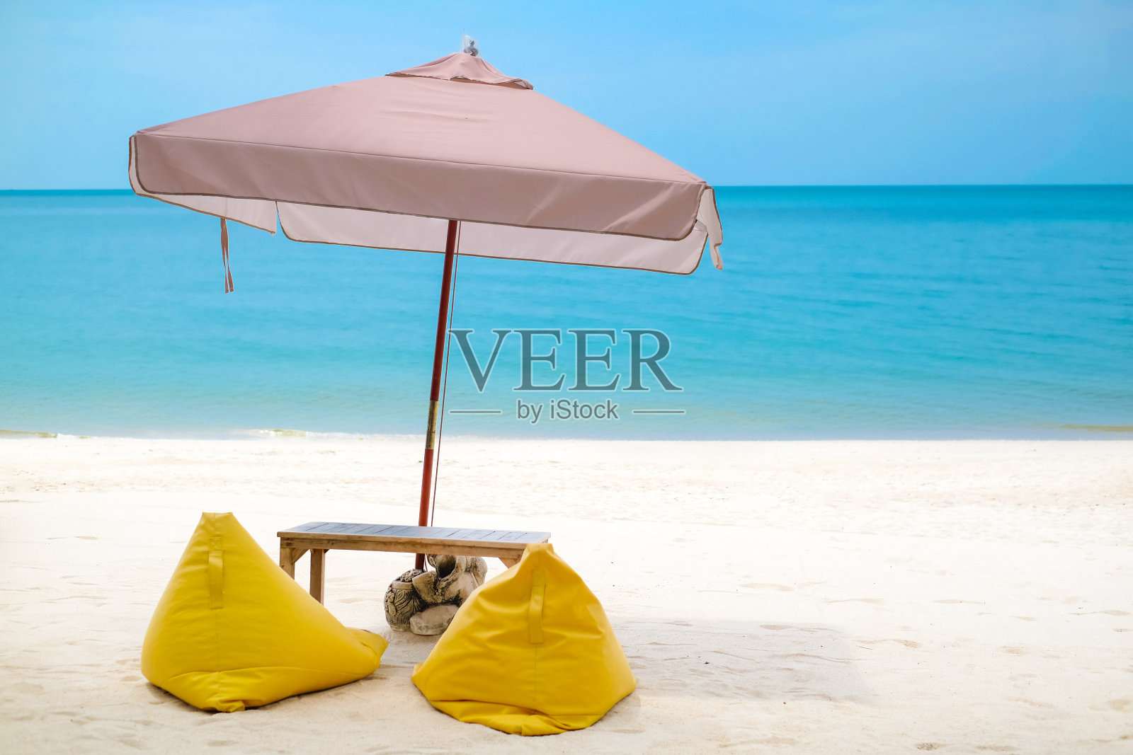 美丽的热带海滩，泰国。白色沙滩上的黄色沙滩床，豆袋椅和雨伞，可以放松地看着蓝色的大海。在假期概念中休息。照片摄影图片