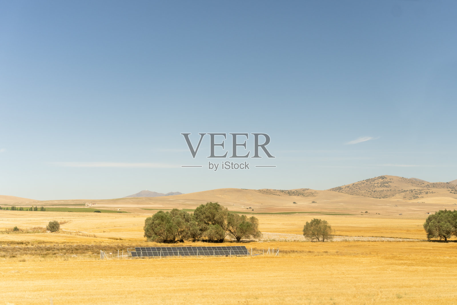 沙漠景观中的太阳能电池板、被太阳晒焦的草地和遥远的山脉。可再生能源，环保。照片摄影图片