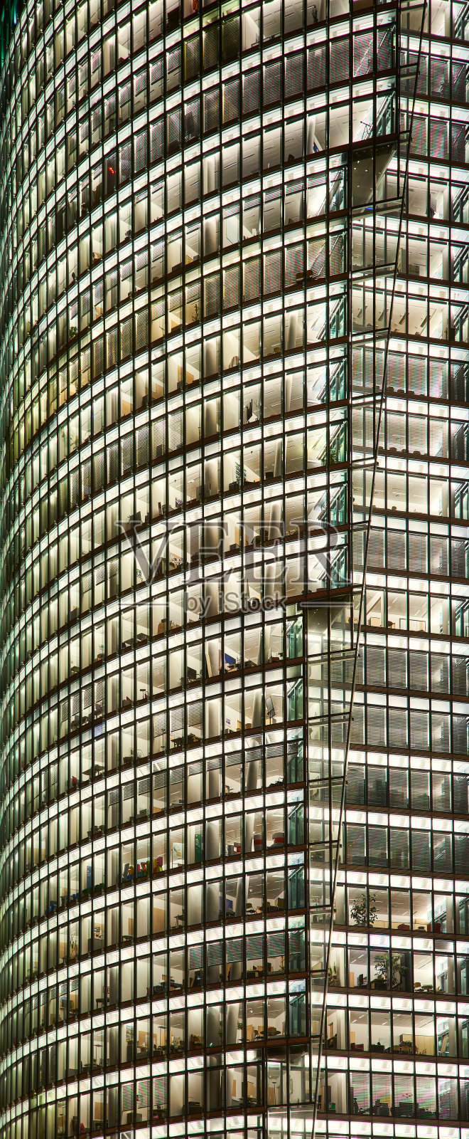 夜间灯火通明的摩天大楼的正面。高大的建筑外观，有明亮的窗户图案。跨国公司或办公总部浪费电力照明商业大楼-波茨坦广场，德国柏林照片摄影图片