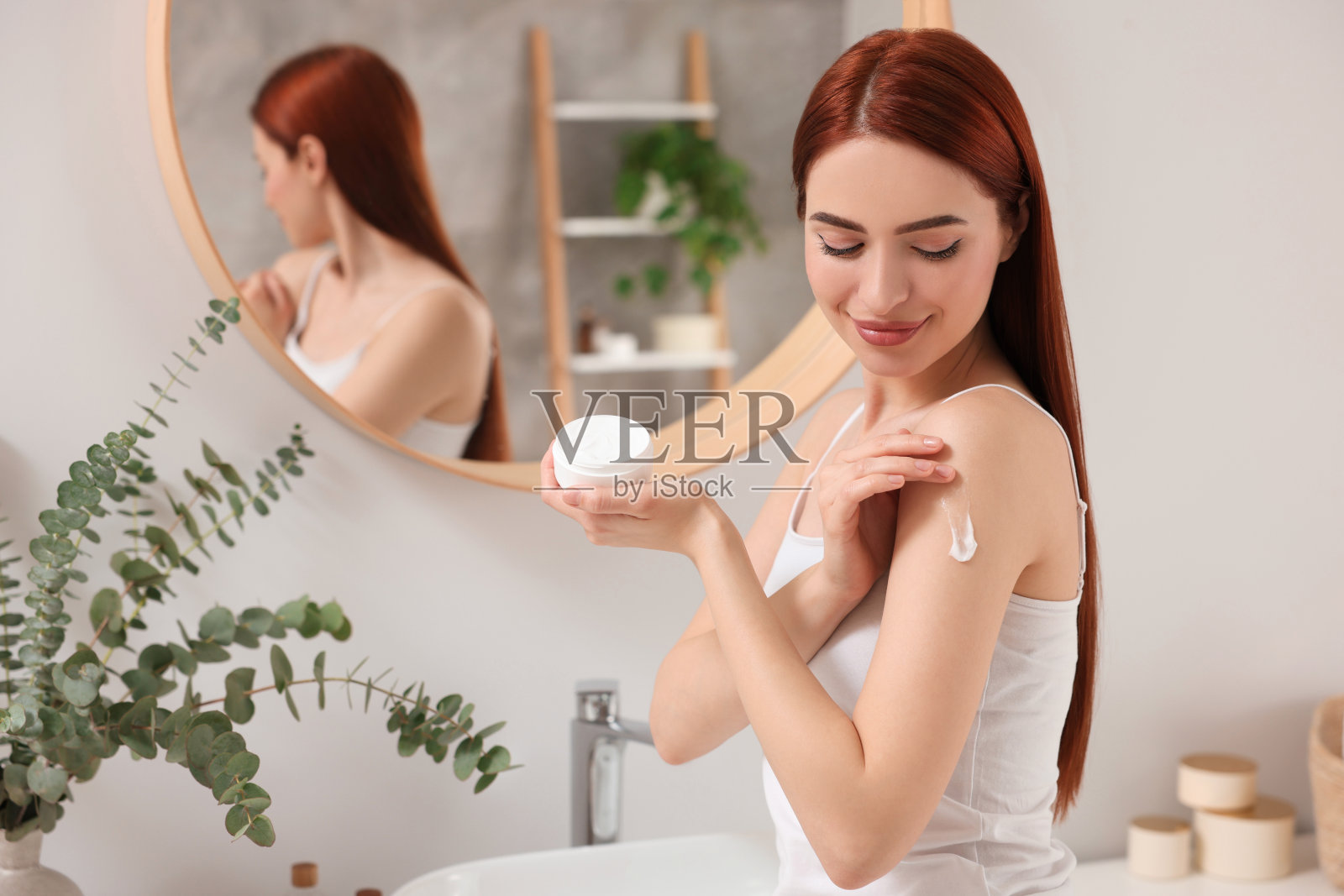 美丽的年轻女子在浴室里把身体霜涂在肩膀上，留出文字的空间照片摄影图片