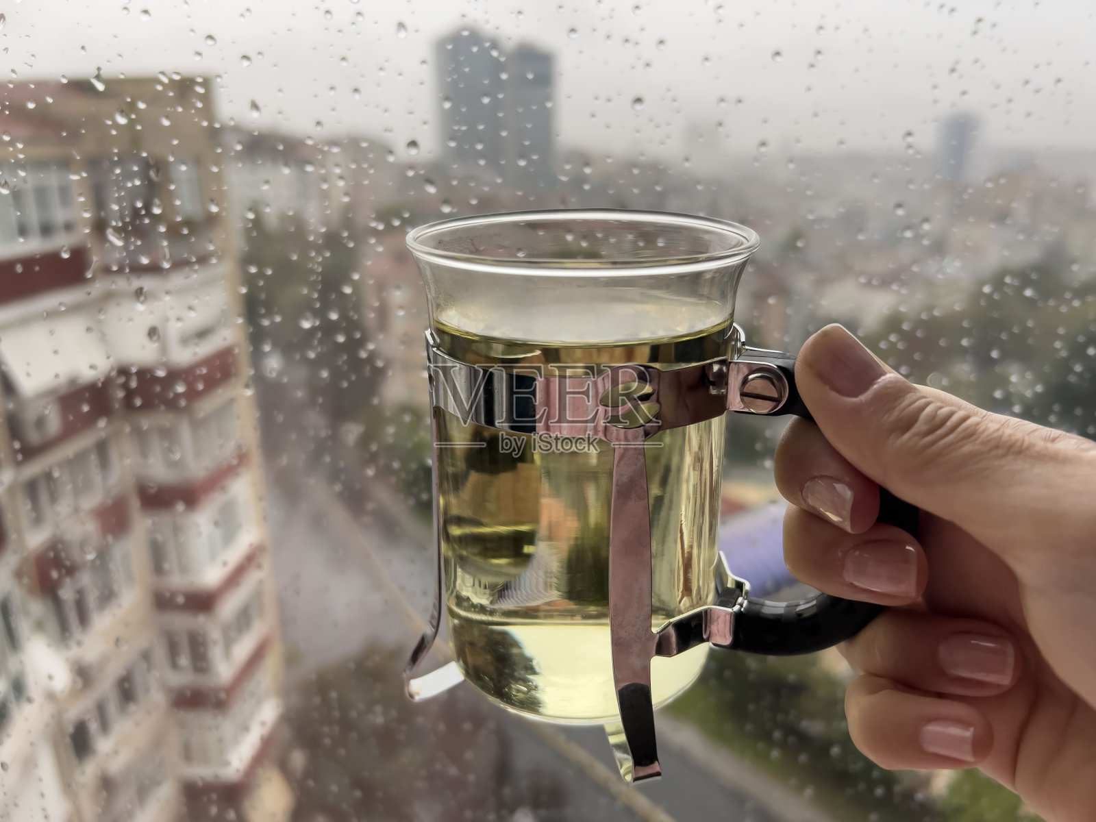 下雨天，手捧一杯凉茶在城市上空漫步照片摄影图片