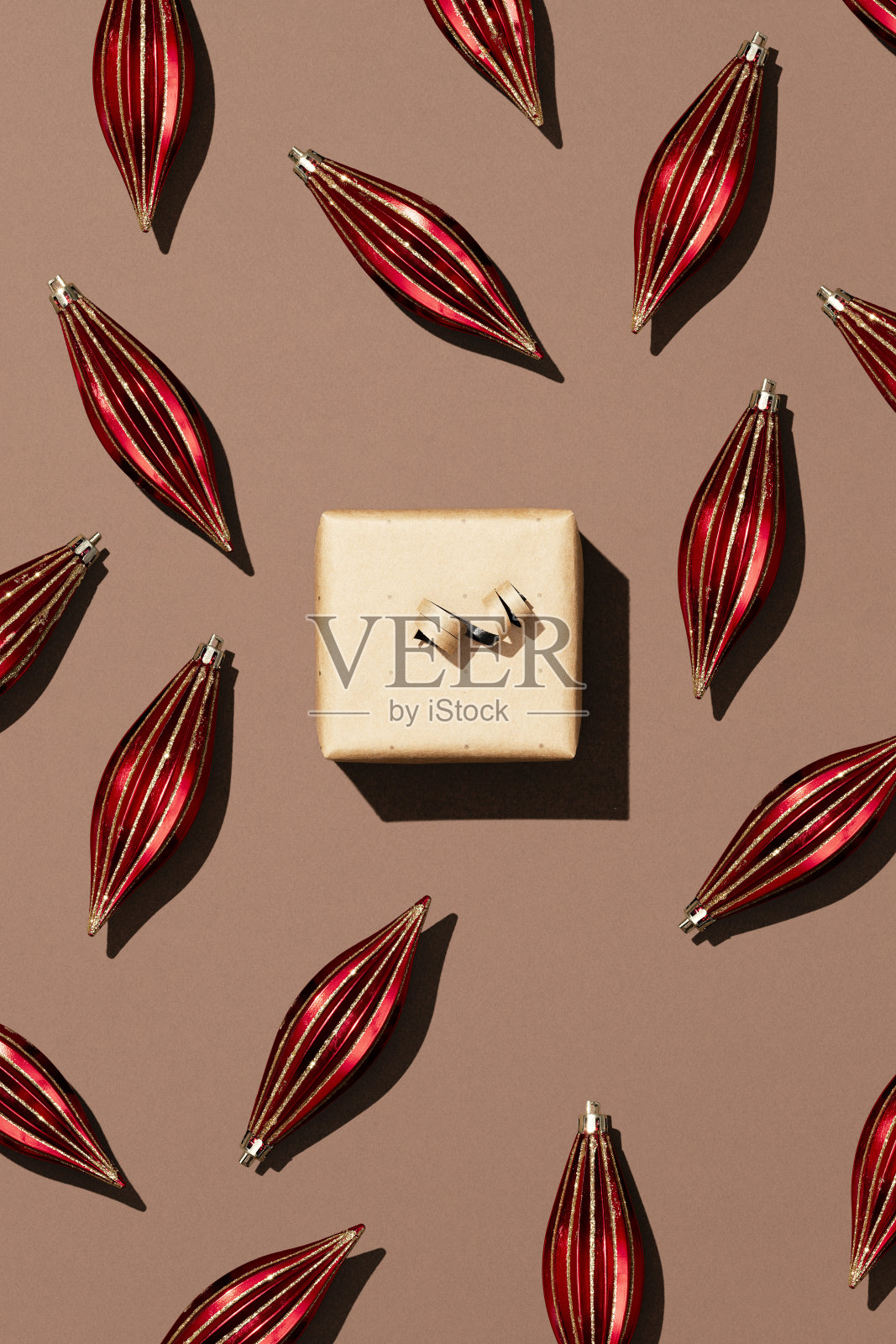 手工花礼盒与闪亮的圣诞球在棕色背景。照片摄影图片