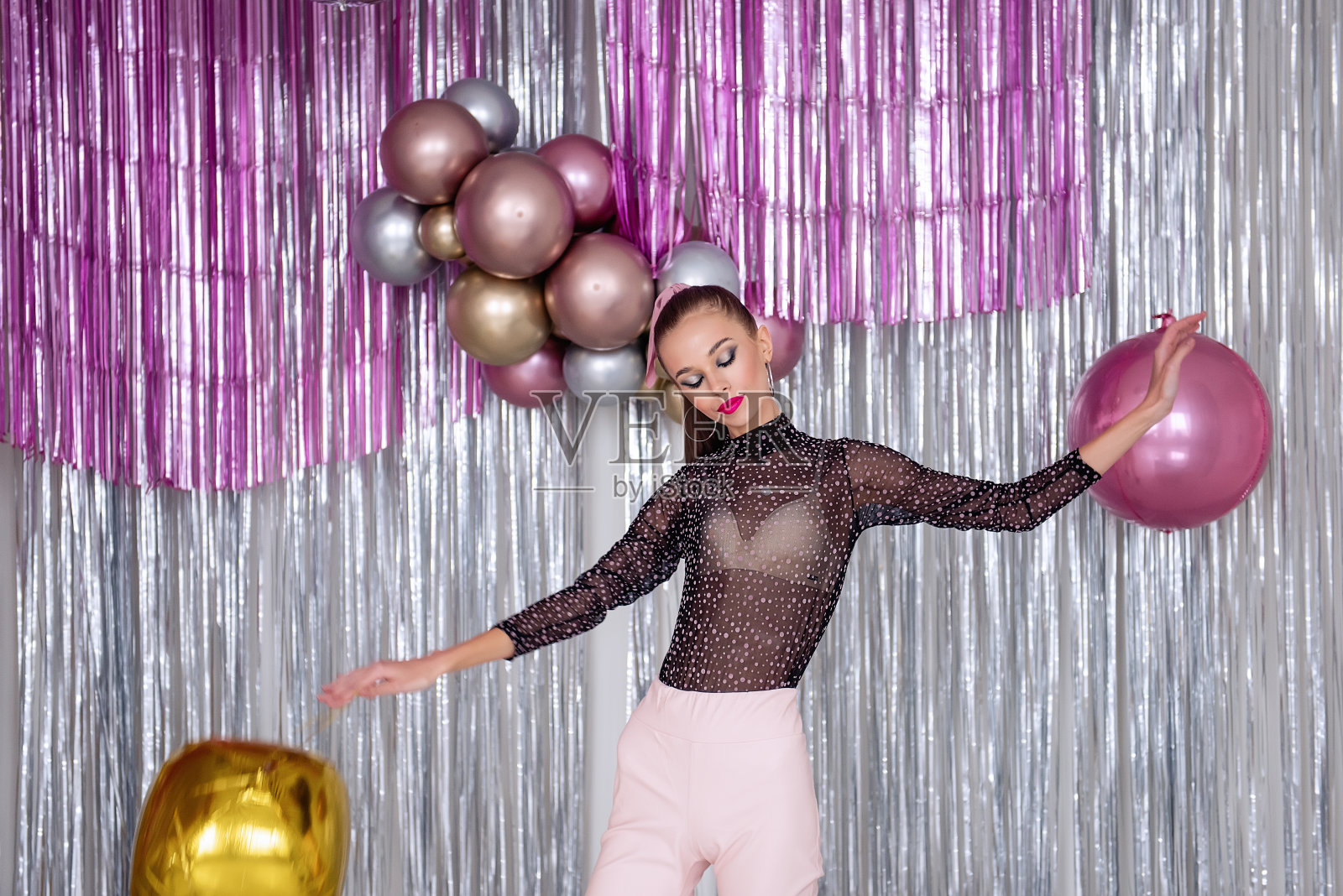 跳舞疯狂的时尚女孩与美丽的化妆。模特们正在玩闪闪发光的气球。新的一年照片摄影图片