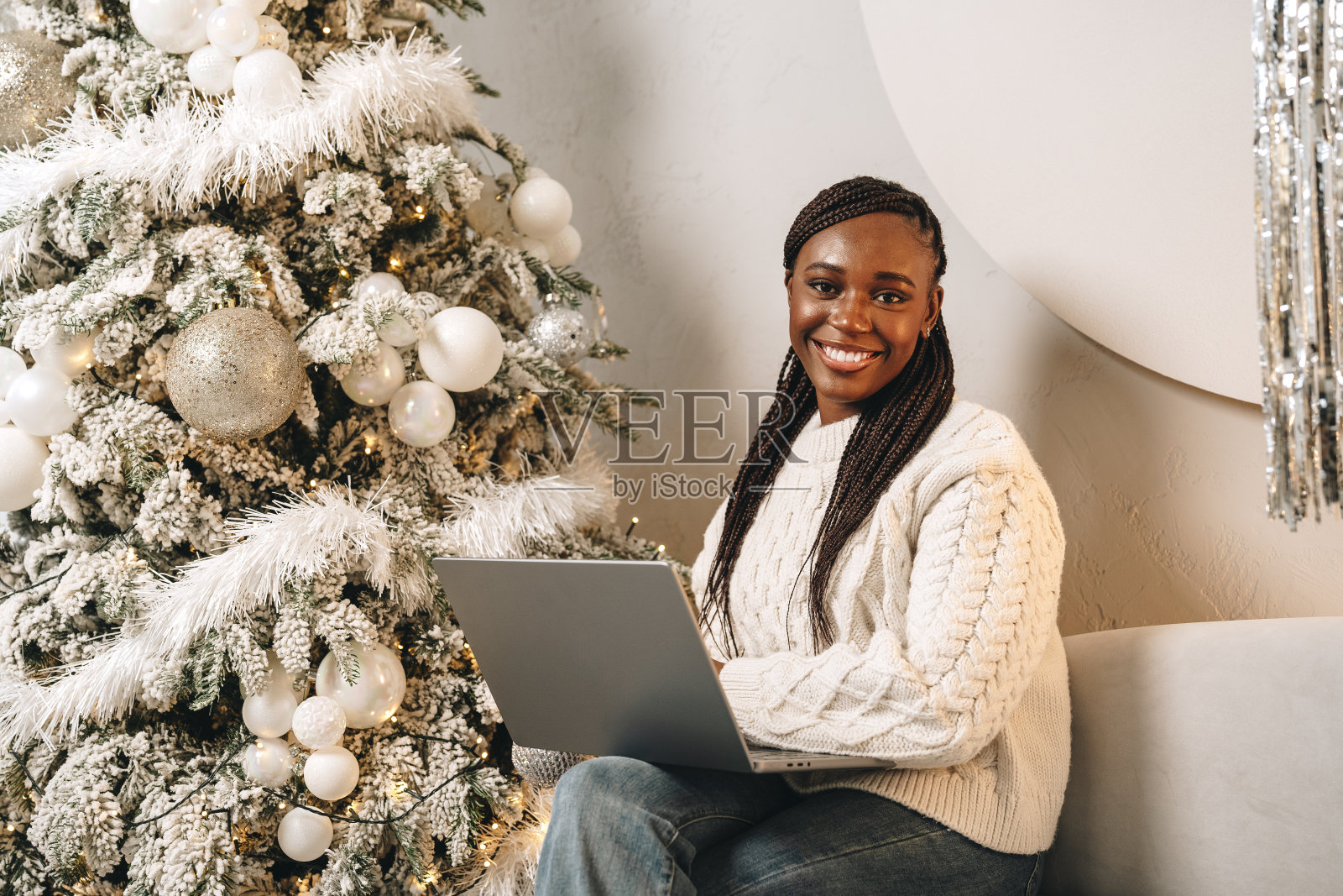 年轻漂亮的非洲女性坐在家里的圣诞树旁，拿着笔记本电脑照片摄影图片