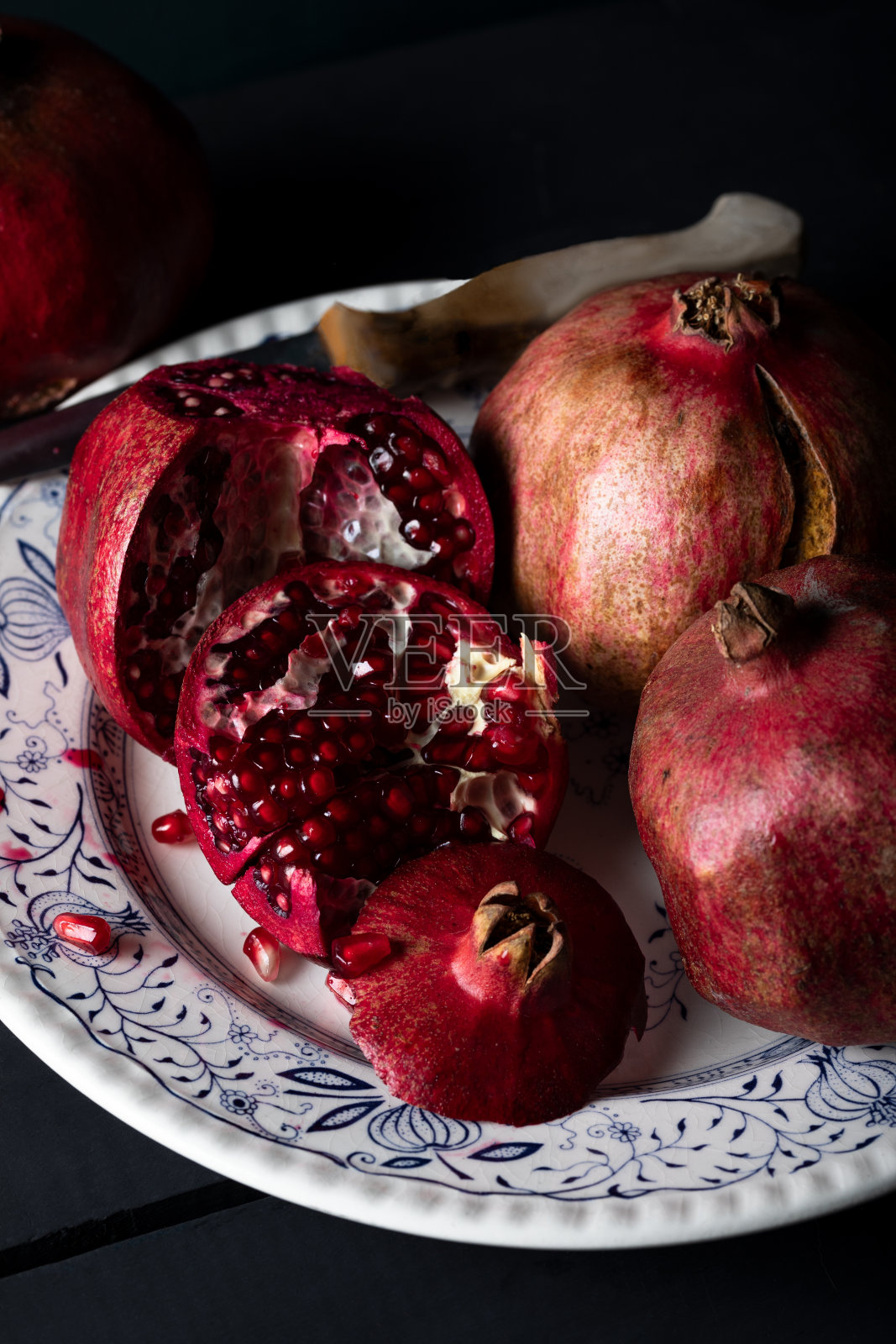 新鲜的石榴在古老的乡村餐桌静物在黑暗的色调。照片摄影图片
