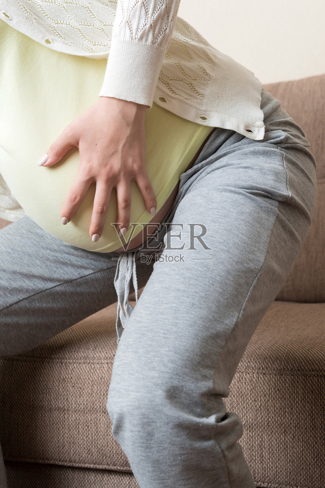 这位准妈妈背部疼痛，想坐在沙发上照片摄影图片