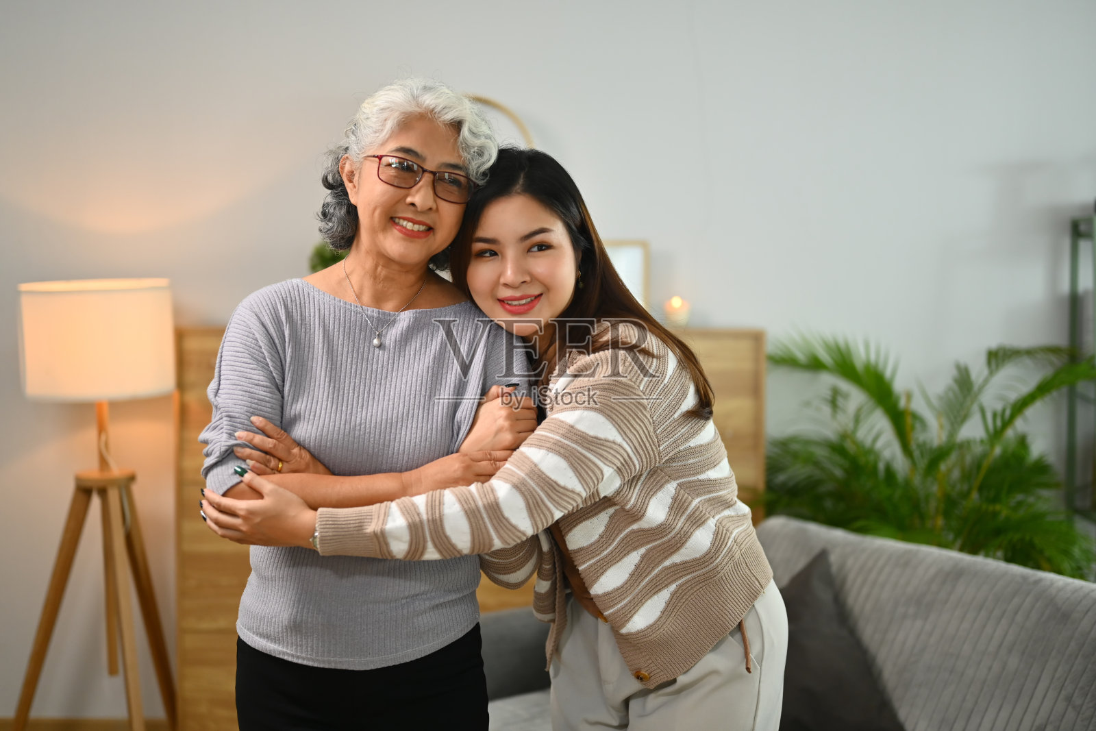 充满爱心的年轻女子用温柔和关怀拥抱着幸福的老母亲照片摄影图片