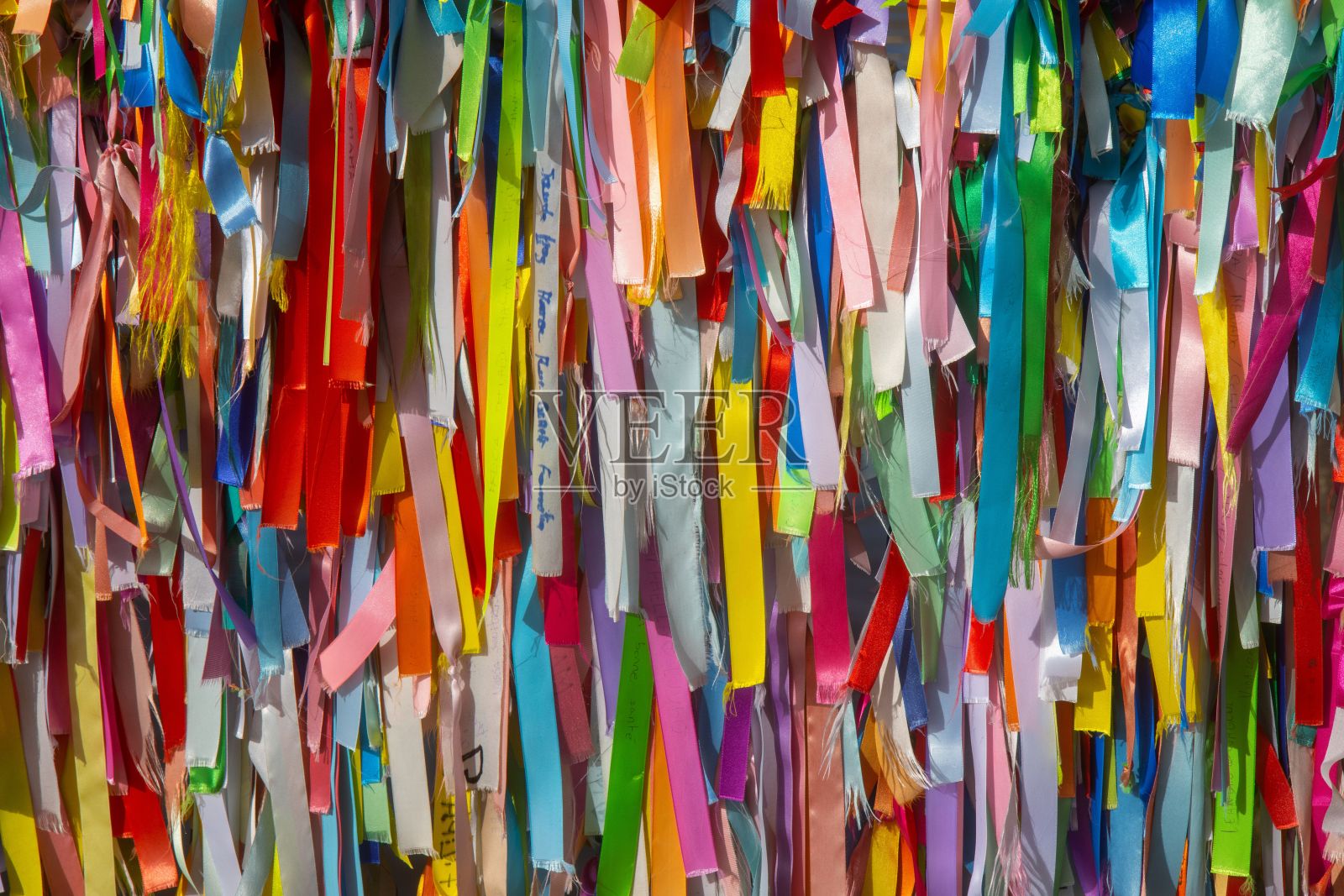 由贴在表面的多种彩色彩带组成的充满活力的墙壁照片摄影图片