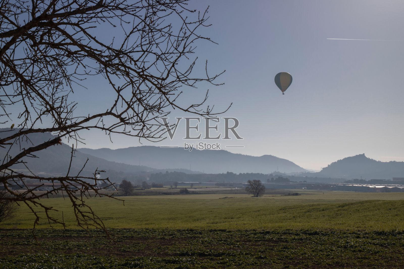 五彩缤纷的热气球在天空中翱翔，郁郁葱葱的连绵群山如画。照片摄影图片