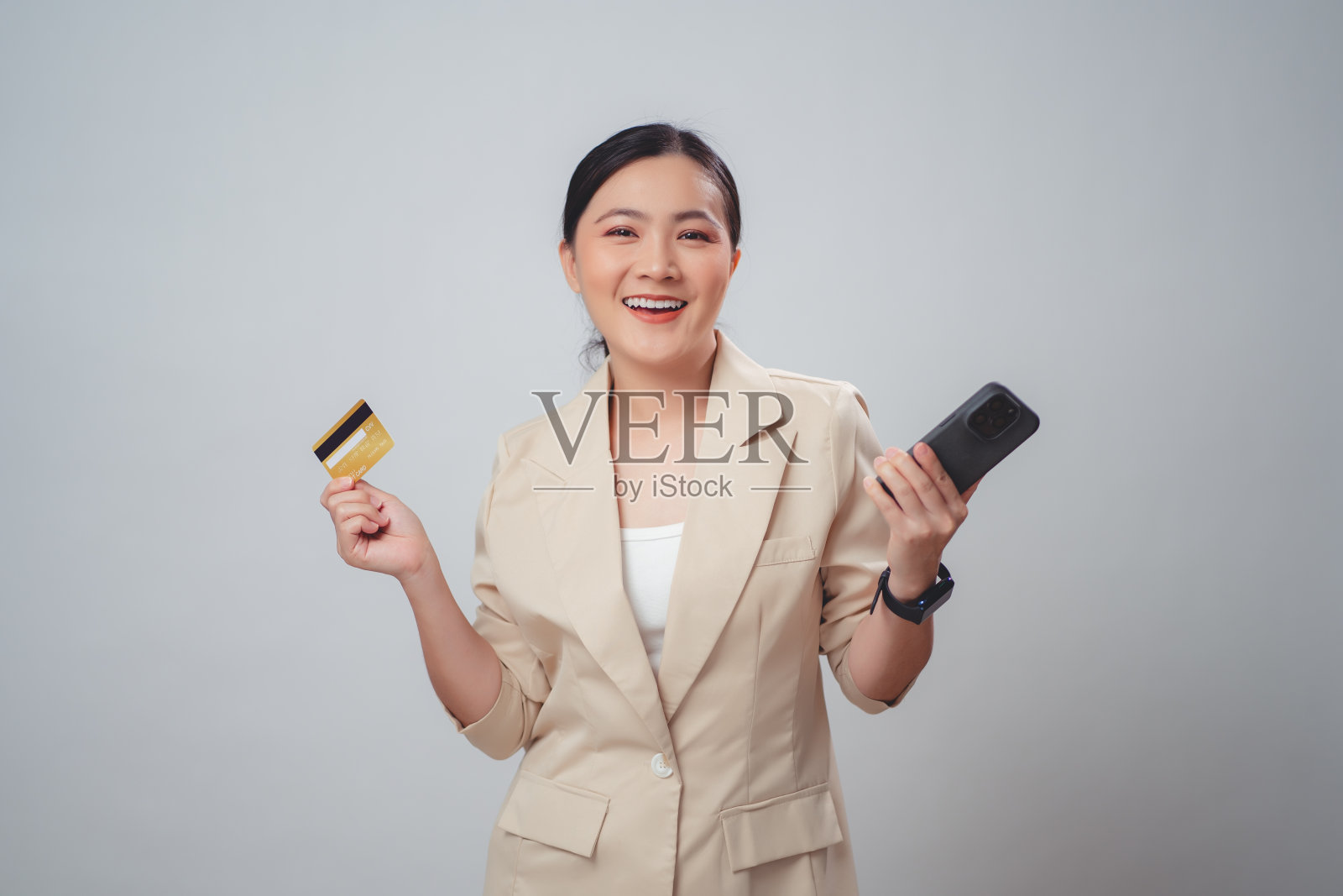 亚洲女性开心兴奋地用智能手机和信用卡在网上购物，孤立在白色背景。照片摄影图片